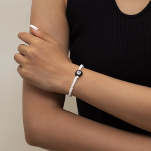 Detalle de pulsera de cuentas con letra N, cuentas acrílicas blancas y margarita