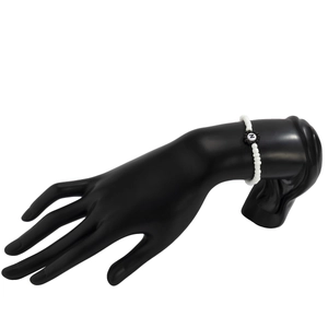 Primer plano de pulsera de cuentas blancas con dije de flor y letra N en modelo de mano