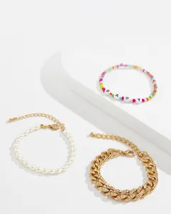Close-up of beaded alphabet bracelet, faux pearl chain, and rhinestone Cuban link set