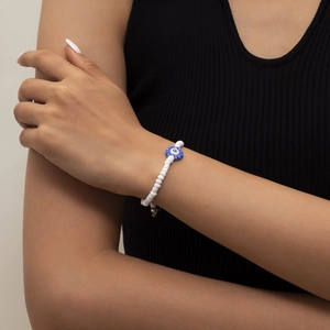 Primer plano detallado de una pulsera de cuentas hecha a mano con dije de flor y letra R