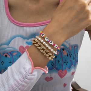 Close-up of stacked gold Cuban chain with rhinestones, pearls, and colorful beads