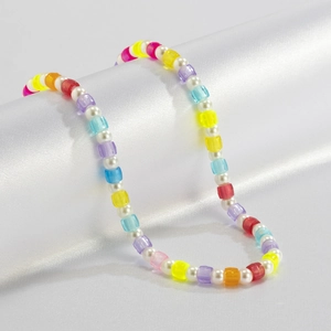Colorful transparent beads and faux pearls necklace on a white silk background