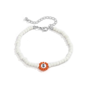 Vista macro de pulsera de cuentas con flor naranja y dije de letra S sobre fondo blanco