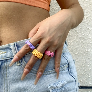 Dettaglio del set di anelli in resina viola, giallo e rosa indossati in stile Y2K