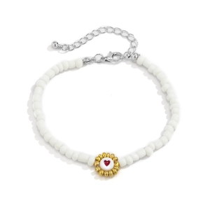Detalle de pulsera de cuentas blancas con dije de girasol dorado y diseño de corazón