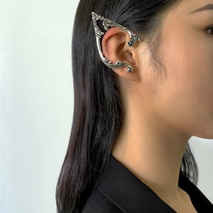 Detailed view of silver gothic ear cuff with baroque scroll texture on model's ear