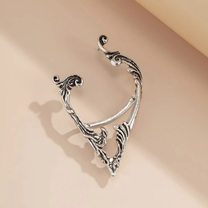 Macro detail of retro silver ear cuff with intricate gothic hollow floral patterns
