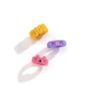 Dettaglio di anelli in resina colorata con design a forma di orso rosa e mostro