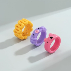 Dettaglio di tre anelli in resina con forme di orso e animali in colori vivaci