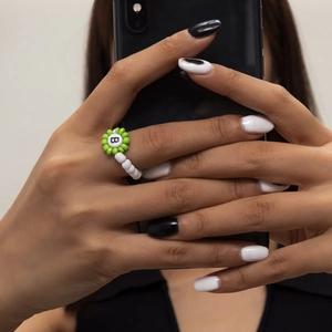 Primer plano del anillo de cuentas verdes y blancas con la letra B en la mano