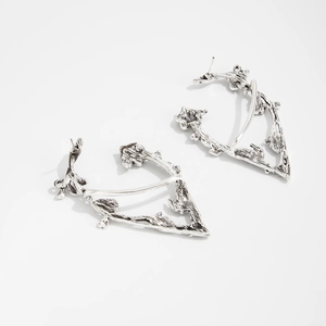 Detailed macro view of irregular vintage silver elf ear cuffs with dark branch texture
