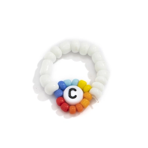 Detalle macro del anillo de cuentas coloridas con cuentas blancas y cuenta central letra C