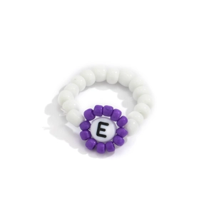 Detalle de anillo de cuentas con letra E blanca y motivos de flores púrpuras