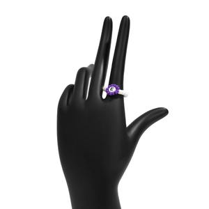 Detalle de anillo artesanal con cuentas moradas y letra E en soporte de modelo negro