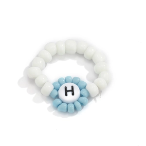 Primer plano de anillo hecho a mano con cuentas blancas y azul claro y la letra H
