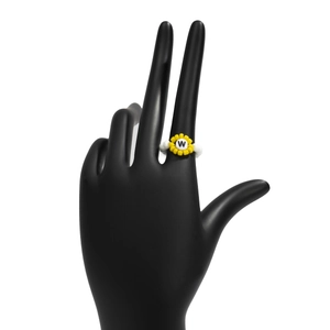 Detalle de anillo de cuentas de girasol con letra W en soporte de joyería negro