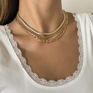 Primer plano de collar multicapa dorado con cadenas estilo serpiente, Figaro y eslabón
