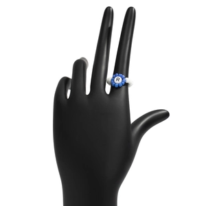 Primer plano de un anillo de cuentas azules y blancas con la letra R negra en modelo de mano