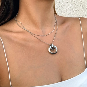Detalle del collar de doble capa de plata con colgante de tres anillos entrelazados