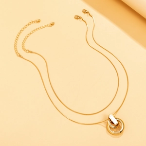 Detalle del colgante de doble anillo entrelazado dorado en una cadena de serpiente
