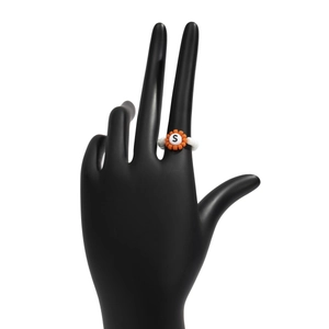 Detalle de anillo de cuentas hecho a mano con flor naranja y letra S en modelo de mano negra
