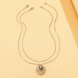 Detalle de collar de doble cadena de serpiente plateada con anillos entrelazados y mosquetón