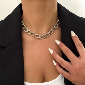 Detailopname van een goudkleurige Cubaanse ketting met glanzende strassteentjes op model