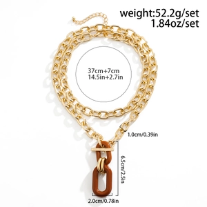 Detail of chunky gold chain necklace with brown resin ring pendant and lobster clasp closure