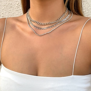 Detalle de collar plateado de tres capas con eslabones cubanos y pedrería sobre la piel