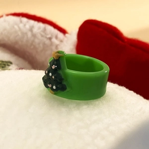 Dettaglio dell'anello a forma di albero di Natale in acrilico verde su tessuto festivo