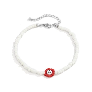 Detalle de collar de cuentas blancas con flor roja y colgante de la letra A