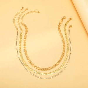 Detalle de collar multicapa dorado con cadena cubana, pedrería y cierre de langosta