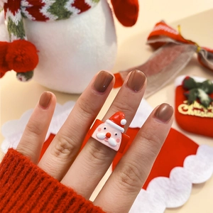 Dettaglio dell'anello in acrilico con Babbo Natale al dito con decorazioni natalizie