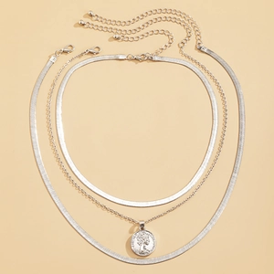 Detalle del collar de tres capas en plata con colgante de moneda y cadenas de espiga elegantes
