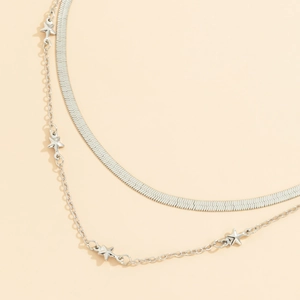 Detalle de un collar de doble capa plateado con cadena de serpiente y colgantes de estrella