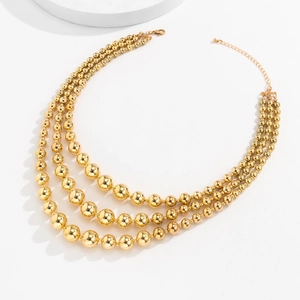 Macro detail of three-layered golden graduated bead necklace with adjustable lobster clasp