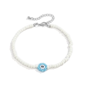 Detalle del collar de cuentas con dije de flor azul y letra H sobre fondo blanco