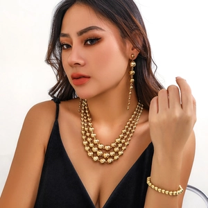 Detailed view of layered golden bead necklace set with matching tassel earrings on model