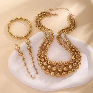 Detail view of a layered golden beaded necklace set with matching bracelet and earrings