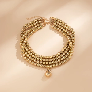 Detail of triple-layer gold bead necklace with a unique lava drop pendant on beige surface