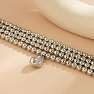 Detail of silver multi-layer beaded necklace featuring an irregular metallic pendant