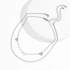 Detalle de collar plateado de capas con cadena de serpiente y tres dijes de corazón