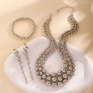 Detailed view of silver layered beaded necklace, bracelet and earrings set on ceramic tray