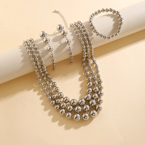 Detailed set of silver beaded necklaces, earrings, and bracelet on white display props