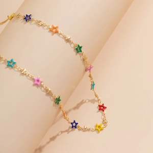 Détail de breloques étoiles en émail coloré sur une fine chaîne de corps en métal doré