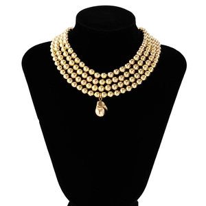 Detail of a four-layer gold beaded choker featuring a metallic teardrop pendant on a neck model
