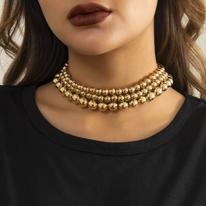 Close-up of a three-layered gold beaded choker necklace featuring a polished mirror finish