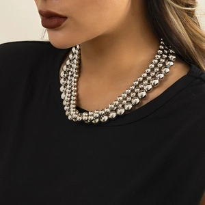 Close-up of triple-layered silver bead chain necklace worn on a black casual shirt