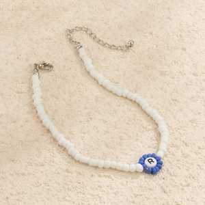 Detalle de collar de cuentas de colores con flor azul y cuenta blanca con la letra R