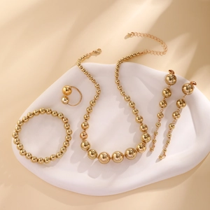 Detailed set of gold beaded jewelry including necklace and earrings on white ceramic tray